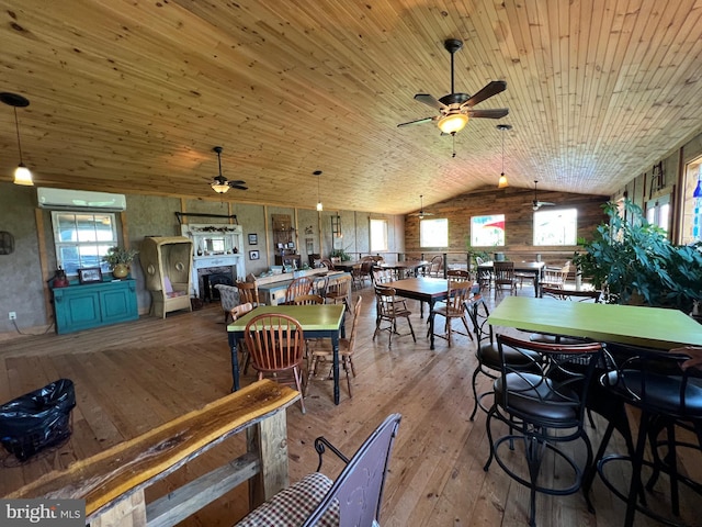 dining area featuring an AC wall unit, vaulted ceiling, wooden ceiling, a fireplace, and wood-type flooring