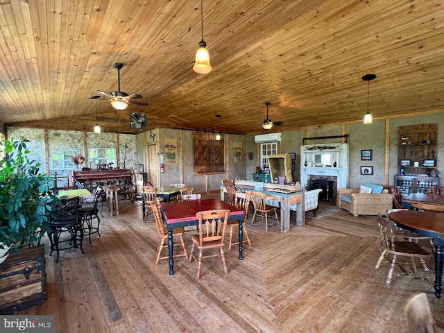 dining room featuring ceiling fan, a fireplace, vaulted ceiling, and hardwood / wood-style flooring