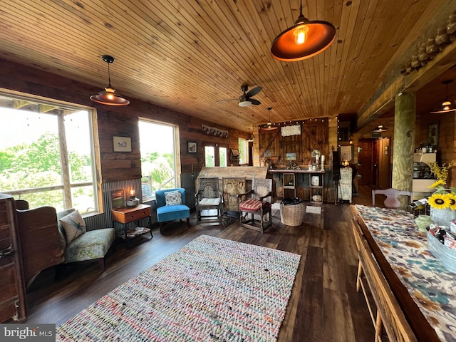 living room with dark wood-type flooring, ceiling fan, wooden walls, and a fireplace