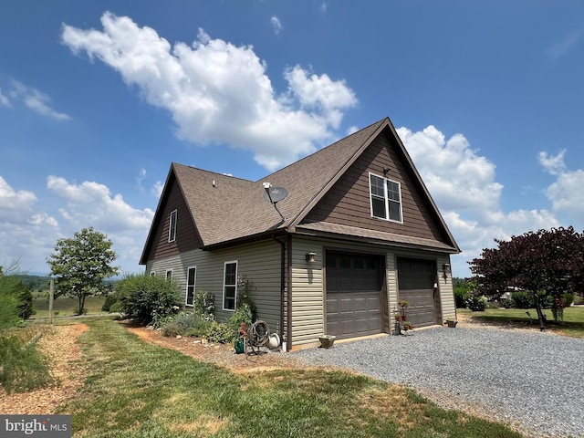 view of side of property featuring gravel driveway, a garage, and roof with shingles