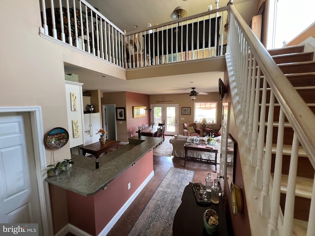 kitchen featuring ceiling fan, carpet floors, white refrigerator with ice dispenser, and a towering ceiling