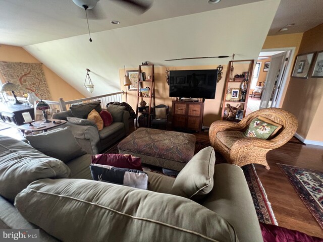 living area with vaulted ceiling, wood finished floors, baseboards, and ceiling fan