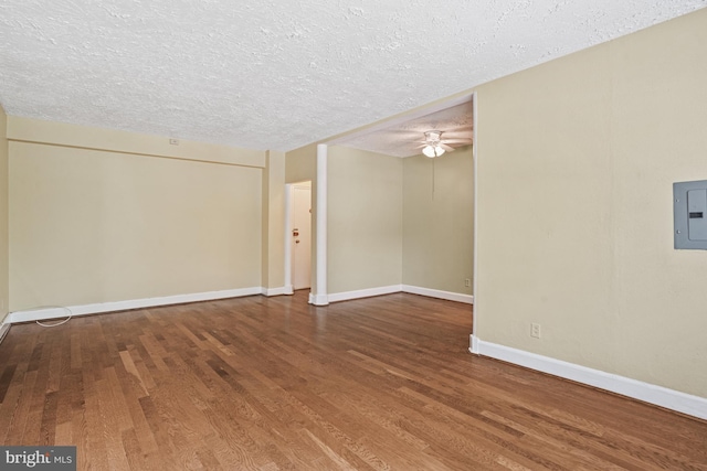 empty room with electric panel, ceiling fan, wood-type flooring, and a textured ceiling