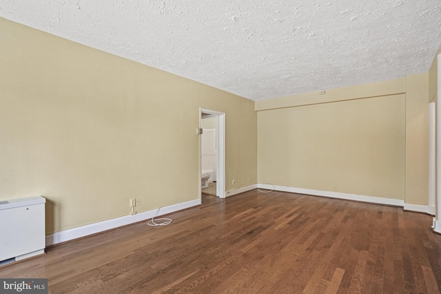 unfurnished room with a textured ceiling and dark hardwood / wood-style flooring