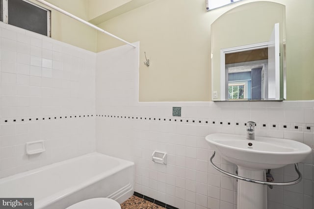 bathroom featuring tub / shower combination, toilet, and tile walls