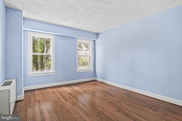 unfurnished room with dark wood-type flooring, plenty of natural light, and a textured ceiling