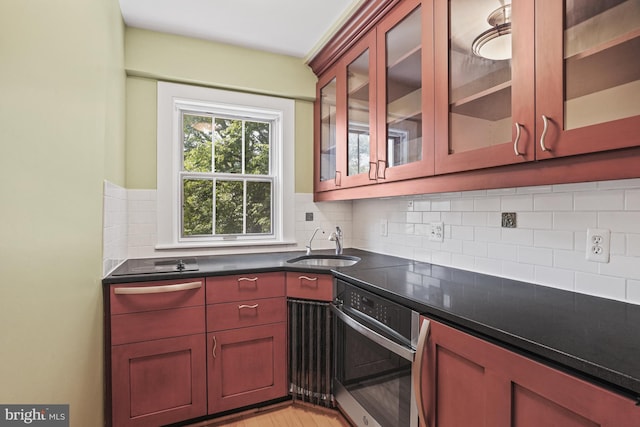 kitchen with sink, light wood-type flooring, oven, and tasteful backsplash