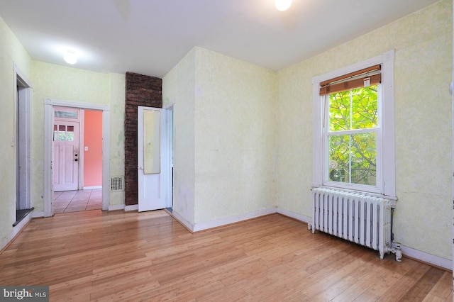 empty room with light wood-type flooring and radiator heating unit