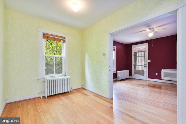 empty room featuring radiator heating unit, light hardwood / wood-style floors, and ceiling fan