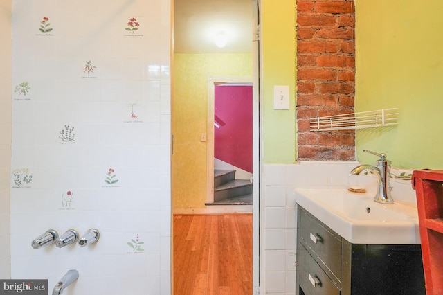 bathroom with tile walls, wood-type flooring, and vanity