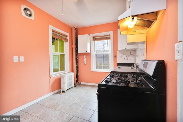 kitchen with sink, radiator heating unit, washer / dryer, white cabinetry, and range hood