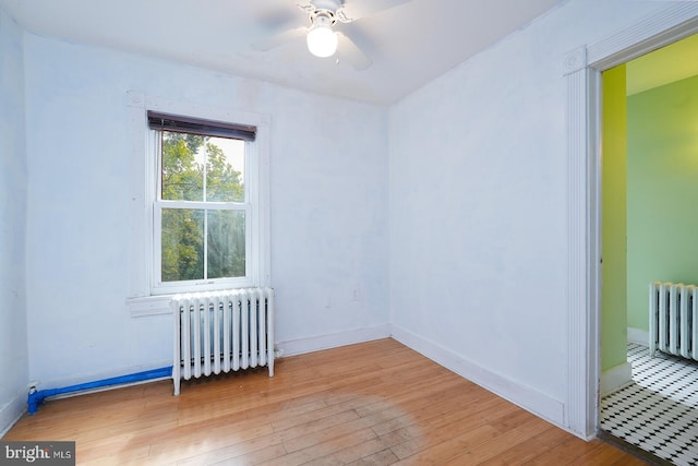 spare room with light wood-type flooring, ceiling fan, and radiator heating unit