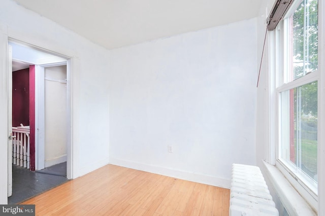 unfurnished room featuring radiator, wood-type flooring, and a wealth of natural light