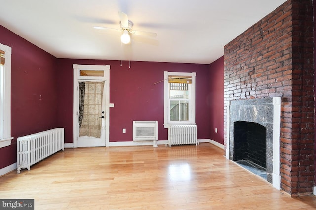 unfurnished living room with heating unit, radiator, ceiling fan, and a fireplace