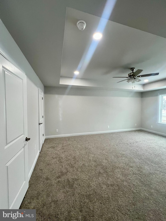 empty room with a tray ceiling, recessed lighting, baseboards, and carpet floors