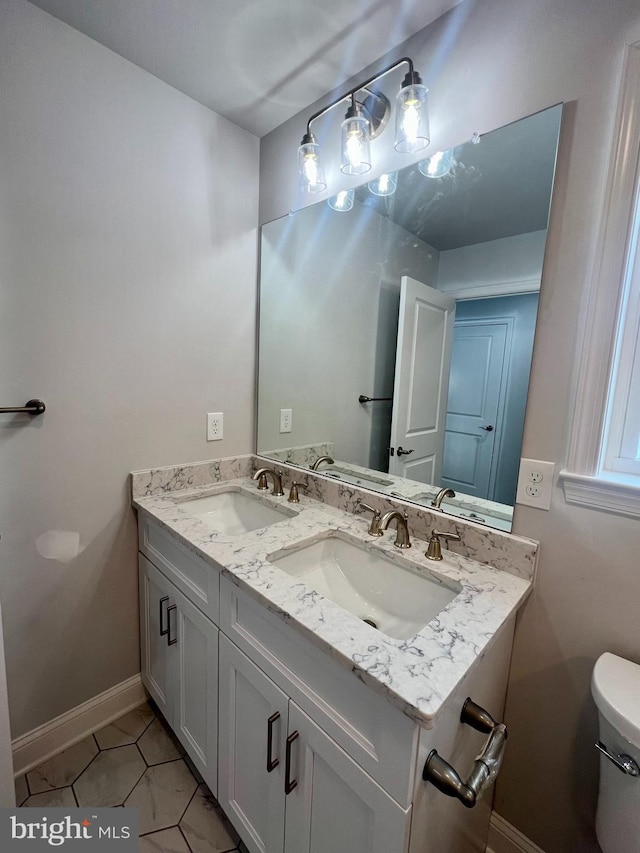 bathroom with double vanity, tile patterned floors, toilet, and a sink