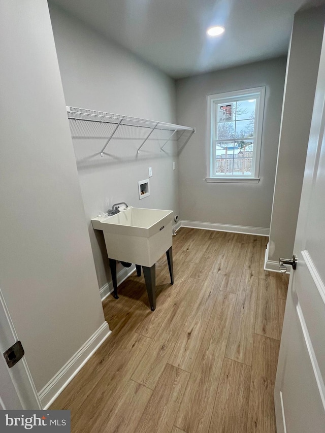 laundry room with hookup for a washing machine, light wood-style flooring, baseboards, and laundry area