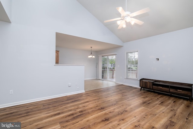 living room featuring hardwood / wood-style floors, ceiling fan with notable chandelier, and high vaulted ceiling