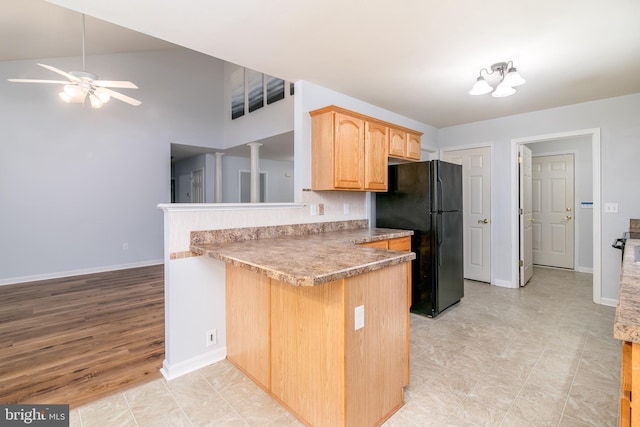 kitchen with baseboards, a peninsula, freestanding refrigerator, a ceiling fan, and ornate columns