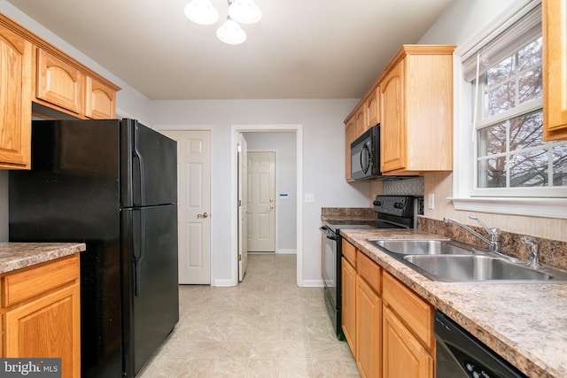 kitchen featuring light brown cabinets, black appliances, baseboards, and a sink