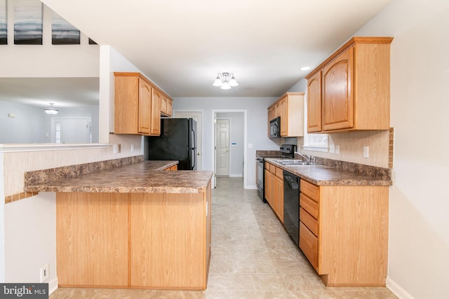 kitchen with tasteful backsplash, baseboards, a peninsula, black appliances, and a sink