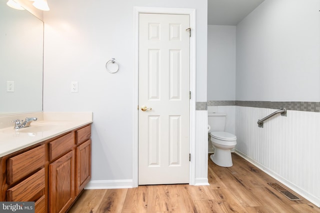 bathroom with visible vents, wainscoting, toilet, and wood finished floors