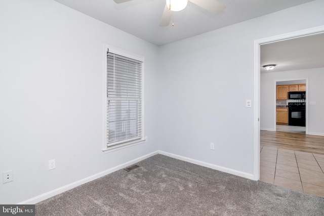 spare room featuring light tile patterned floors, visible vents, baseboards, ceiling fan, and light colored carpet