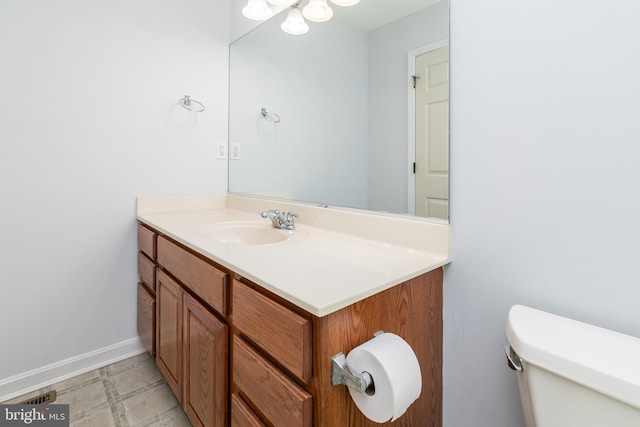 half bath featuring tile patterned floors, toilet, vanity, and baseboards