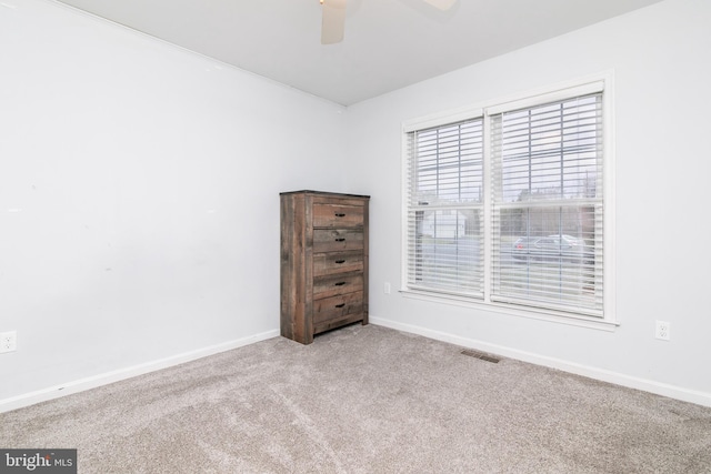 carpeted spare room with visible vents, ceiling fan, and baseboards