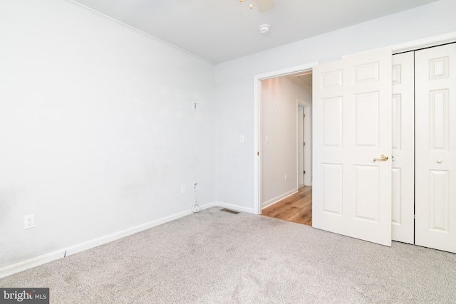 unfurnished bedroom featuring a ceiling fan, visible vents, baseboards, a closet, and carpet flooring