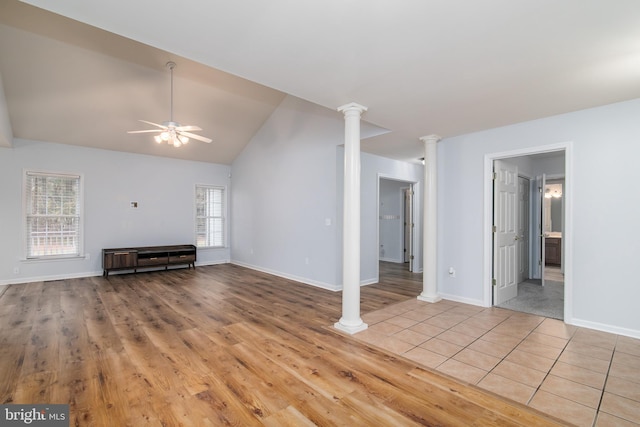 unfurnished living room with plenty of natural light, vaulted ceiling, light hardwood / wood-style flooring, and decorative columns