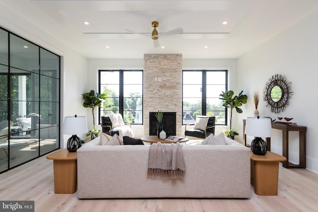 living room featuring a fireplace, ceiling fan, and light hardwood / wood-style floors