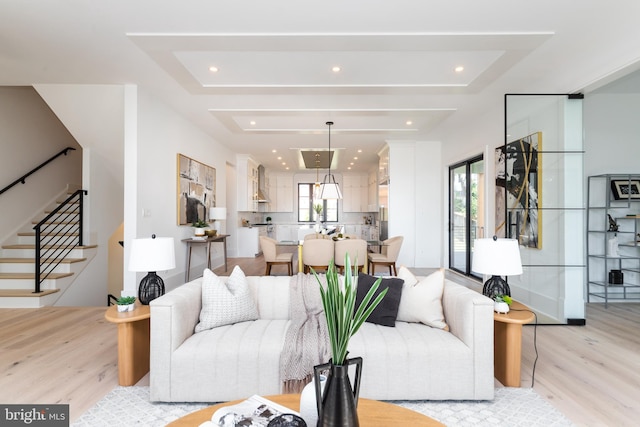 living room featuring a raised ceiling and light wood-type flooring