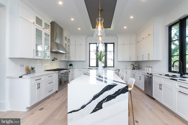 kitchen with wall chimney exhaust hood, a healthy amount of sunlight, stainless steel appliances, and sink