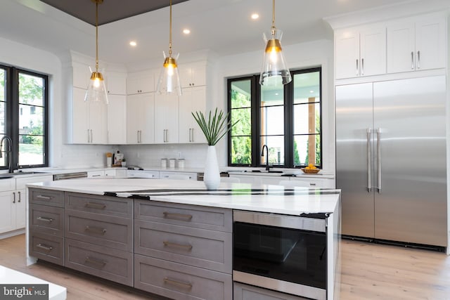 kitchen with gray cabinetry, white cabinets, appliances with stainless steel finishes, and light stone countertops