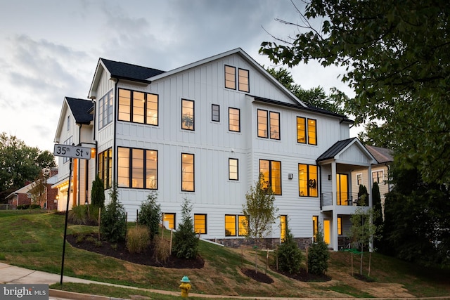 modern farmhouse featuring a front lawn and a balcony