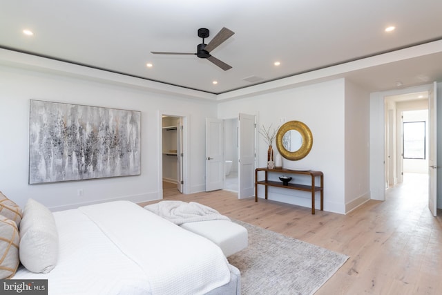 bedroom featuring light wood-type flooring, a walk in closet, ceiling fan, and a closet