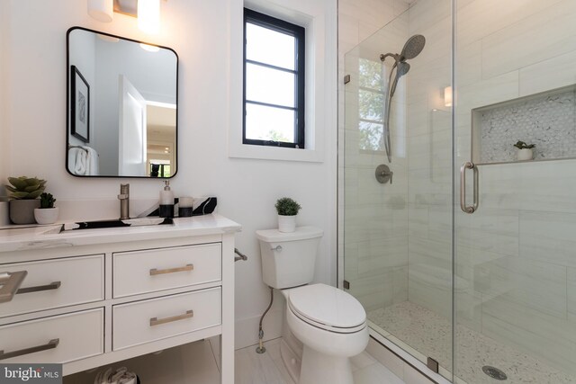 bathroom with a shower with shower door, toilet, and vanity