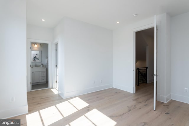 interior space with light wood-type flooring, ensuite bath, and sink