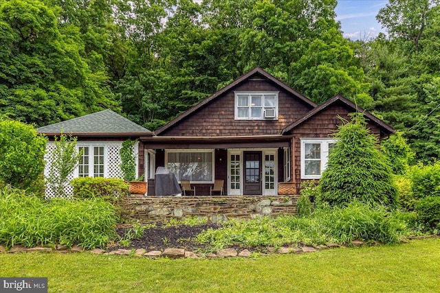 craftsman-style house with covered porch, a front lawn, and cooling unit