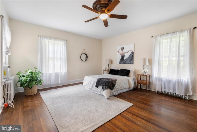 bedroom featuring multiple windows, ceiling fan, dark hardwood / wood-style flooring, and radiator heating unit