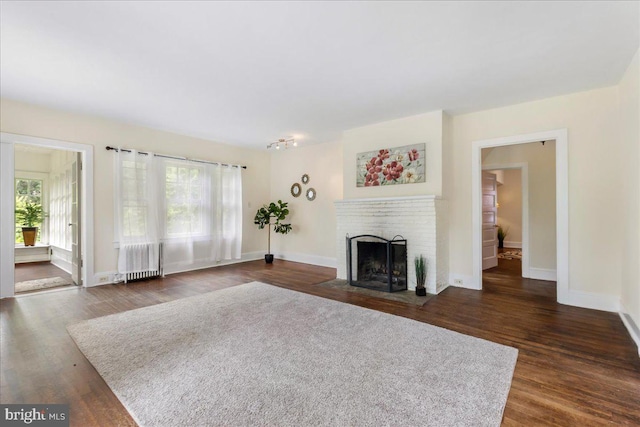 unfurnished living room with radiator, dark hardwood / wood-style flooring, and a fireplace