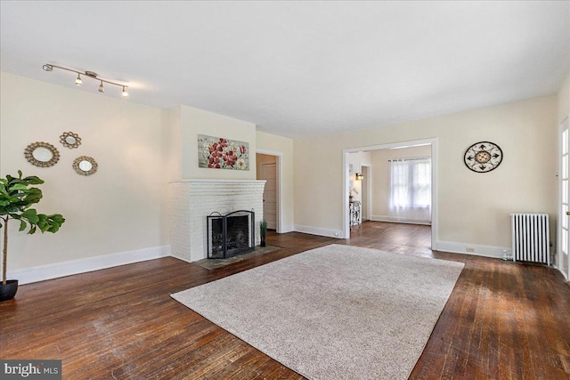 unfurnished living room with dark hardwood / wood-style flooring, radiator heating unit, and a fireplace