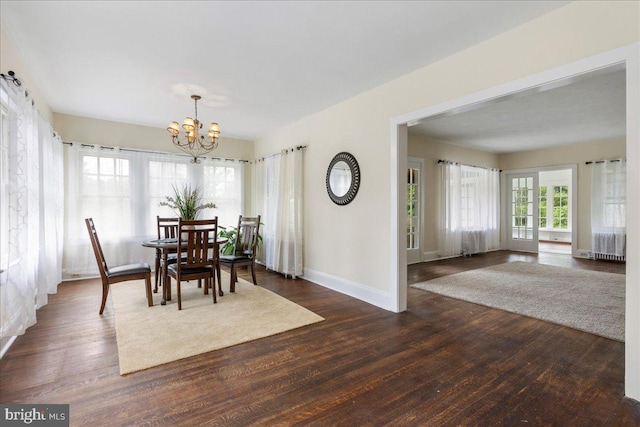 dining room with dark hardwood / wood-style floors and an inviting chandelier