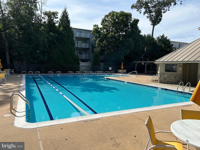 pool with a patio area and fence