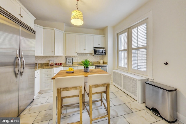 kitchen featuring butcher block countertops, radiator, a center island, appliances with stainless steel finishes, and white cabinets