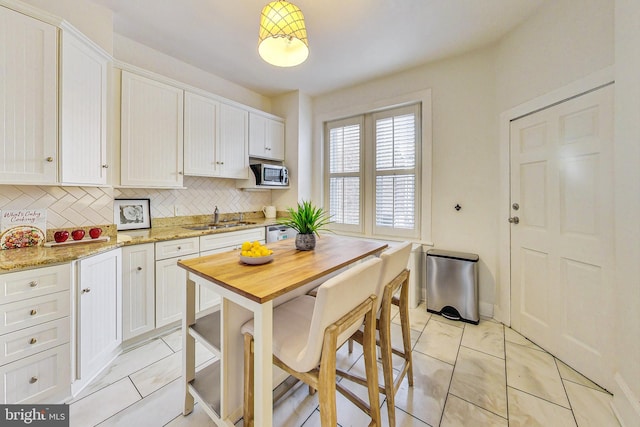 kitchen featuring light stone countertops, light tile patterned floors, and white cabinetry