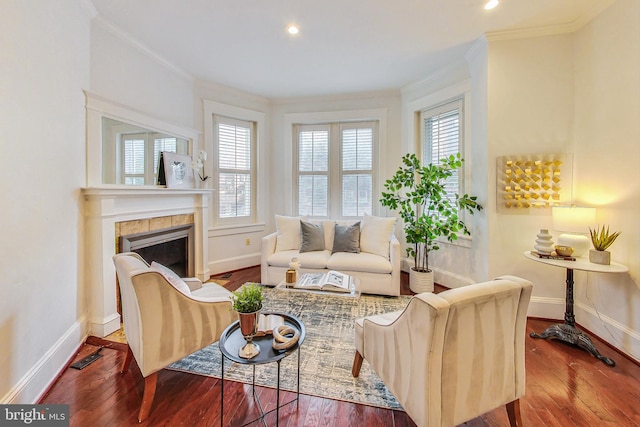 living room with a tiled fireplace, crown molding, a wealth of natural light, and hardwood / wood-style floors