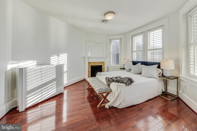 bedroom with a tile fireplace and dark hardwood / wood-style floors