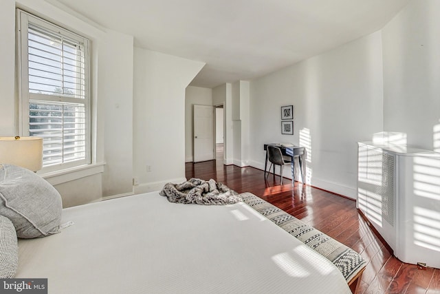 bedroom with multiple windows and dark hardwood / wood-style floors